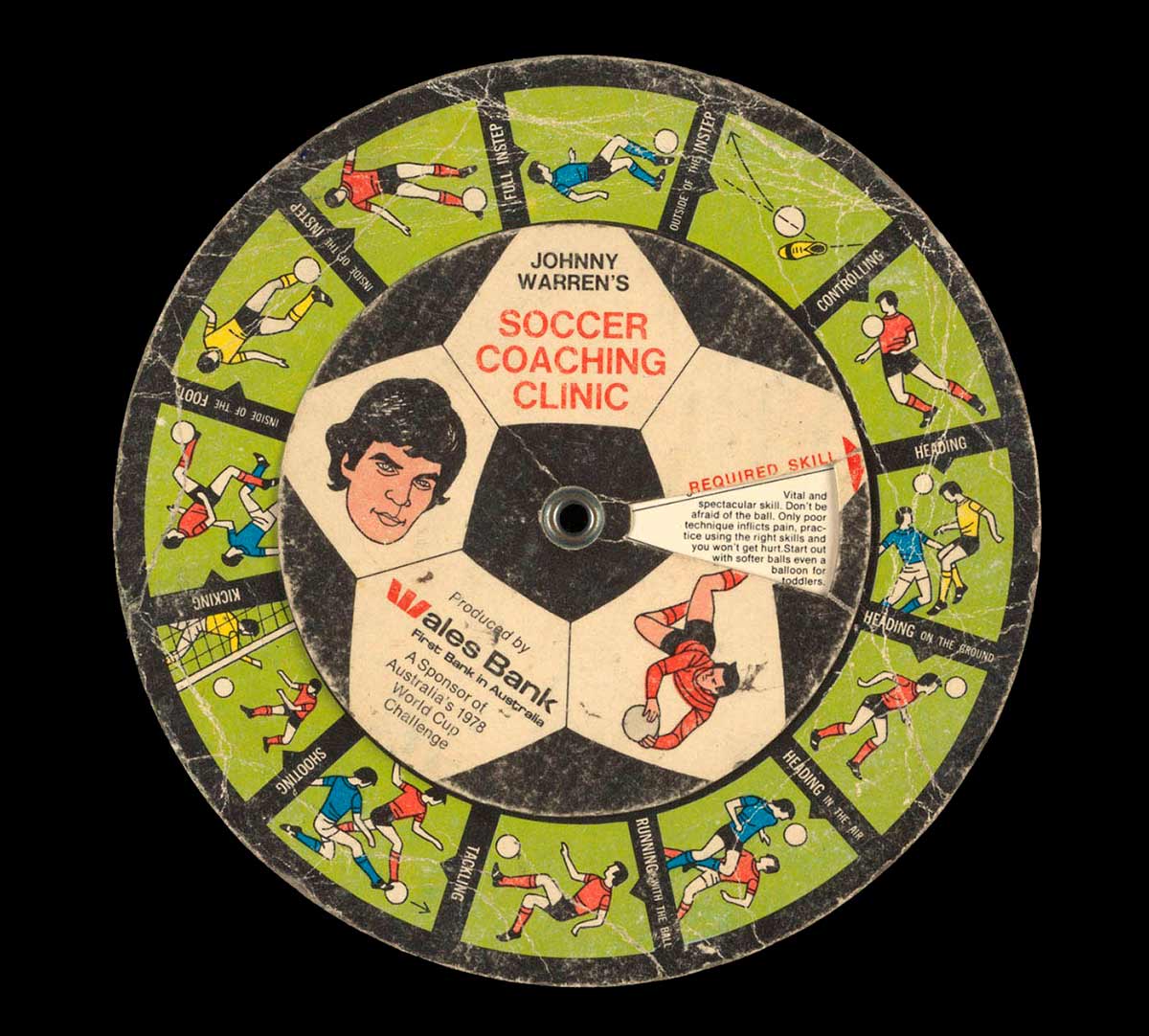 A colour printed cardboard disc with illustrations of football players in different positions, and accompanying descriptive text. There is an illustrated portrait of John Warren at the centre with text 'JOHNNY / WARREN'S SOCCER / COACHING / CLINIC / Produced by / Wales Bank / First Bank in Australia / A Sponsor of / Australia's 1978 / World Cup / Challenge'.