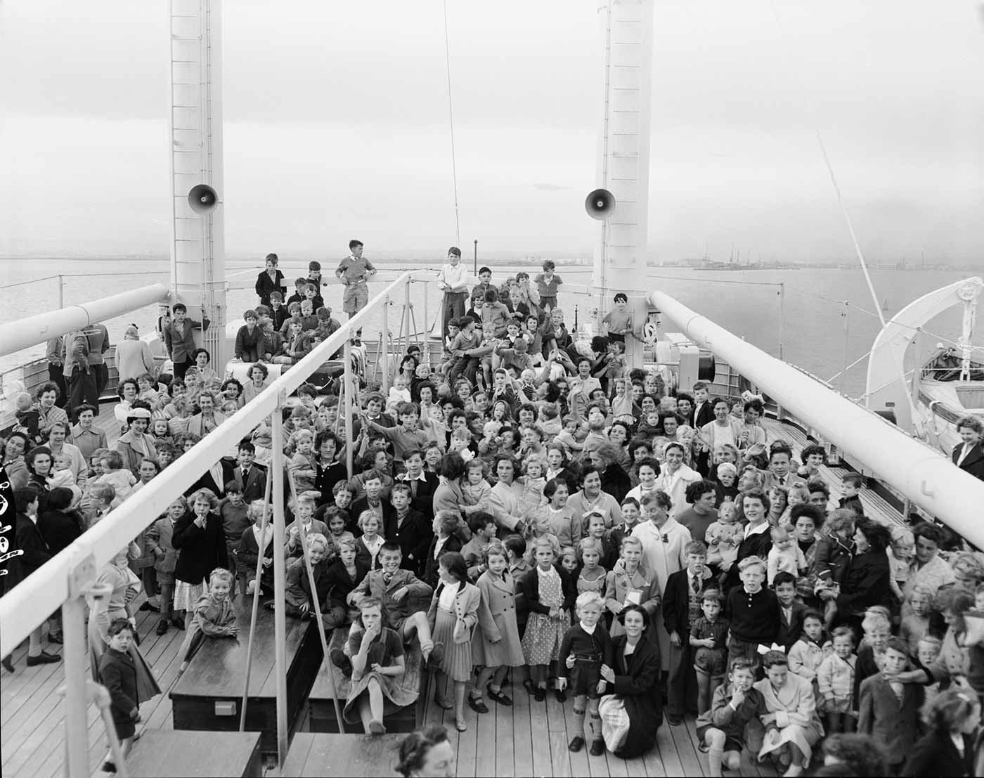 Black and white photo of a large group of children and staff on ship.