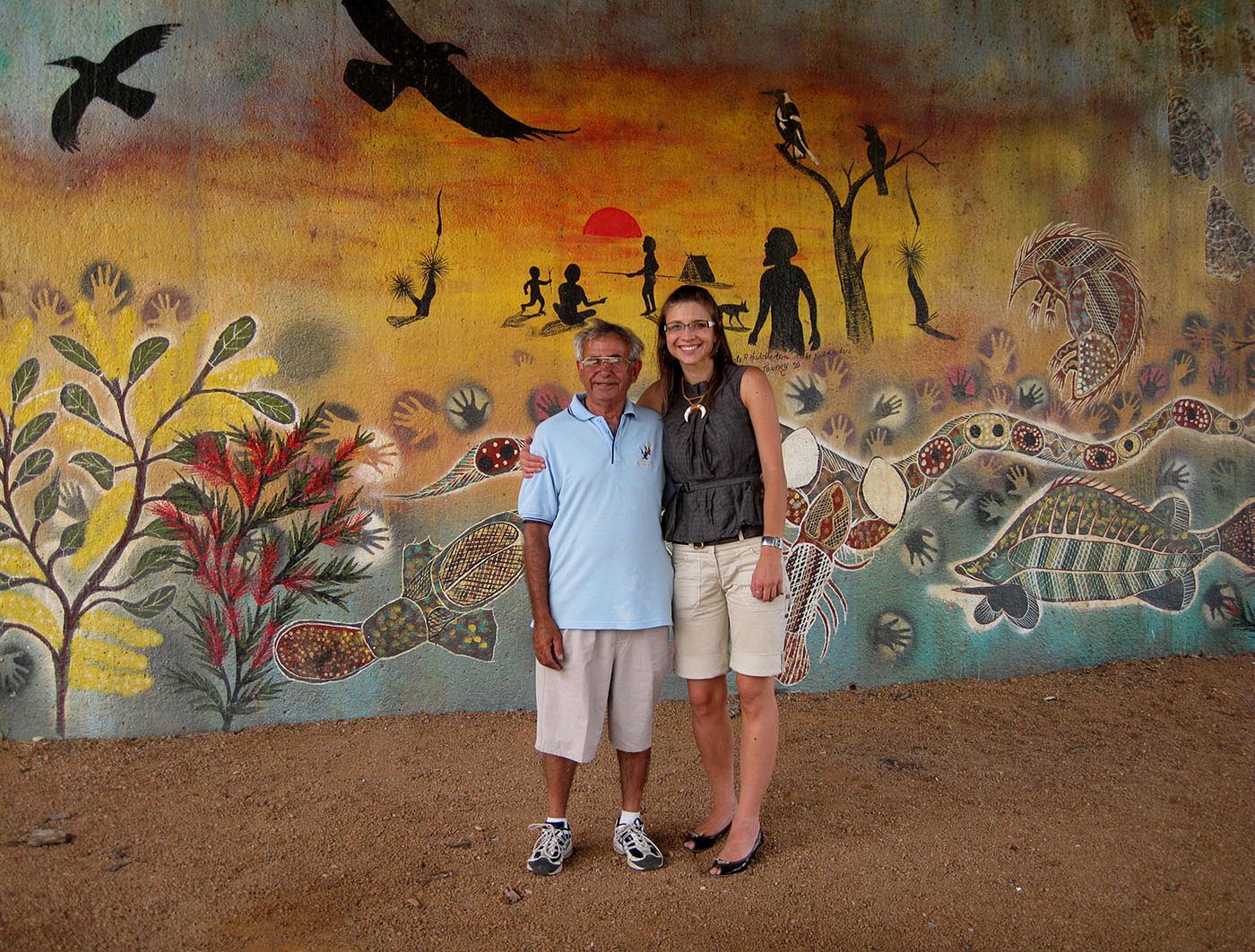 Eric Bell and Karolina Kilian stand in front of a large mural of Aboriginal motifs.