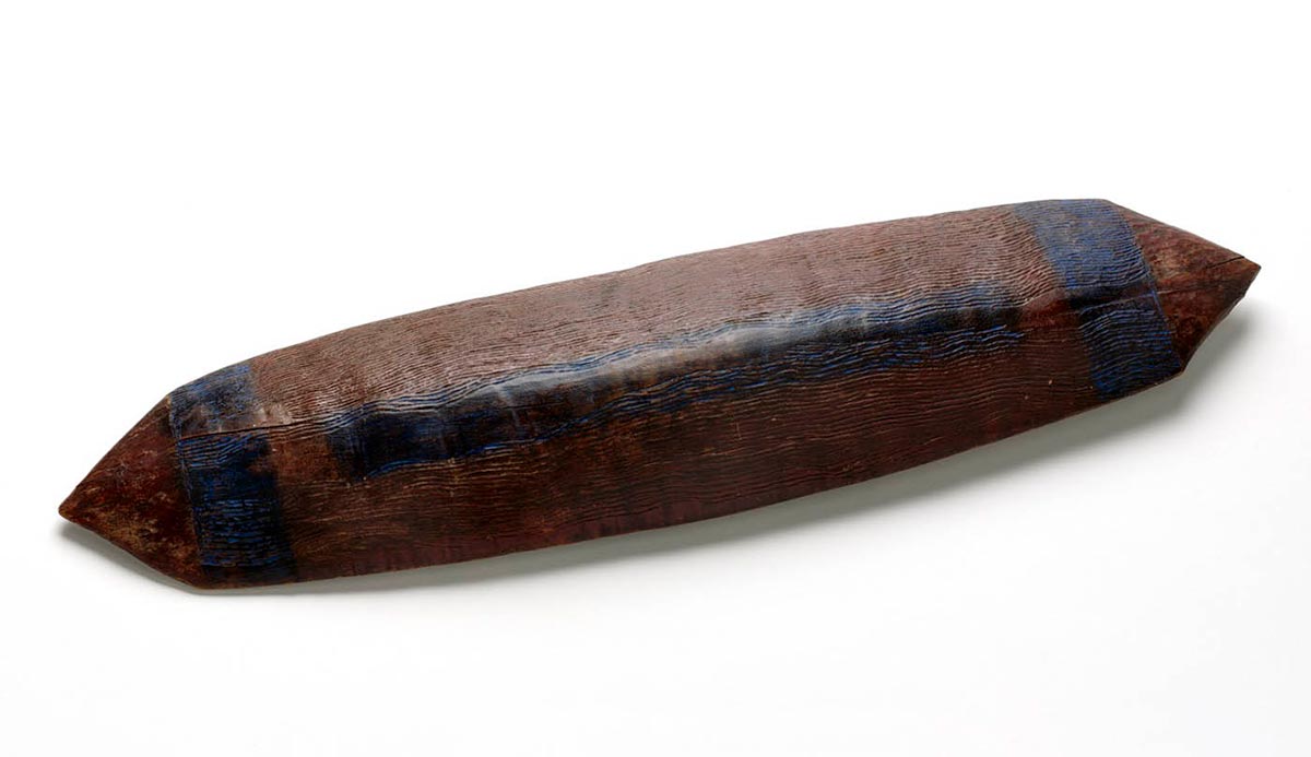 Roughly rectangular-shaped wooden shield with pointed ends. Blue bands are visible at either end and along the centre.